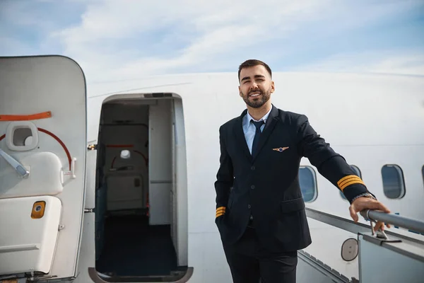 Hezký pilot stojící na schodech do letadla — Stock fotografie