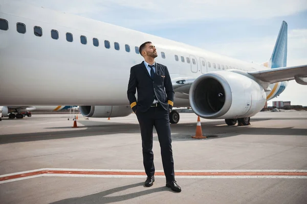 Piloten tittar långt bort när han står på banan nära planet — Stockfoto