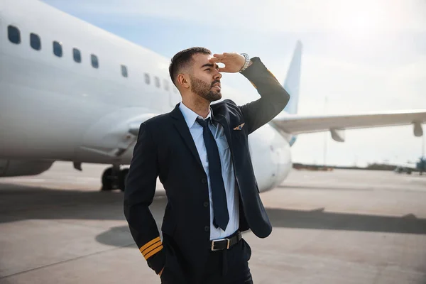 Hombre piloto de avión cubriendo sus ojos mientras mira hacia adelante — Foto de Stock