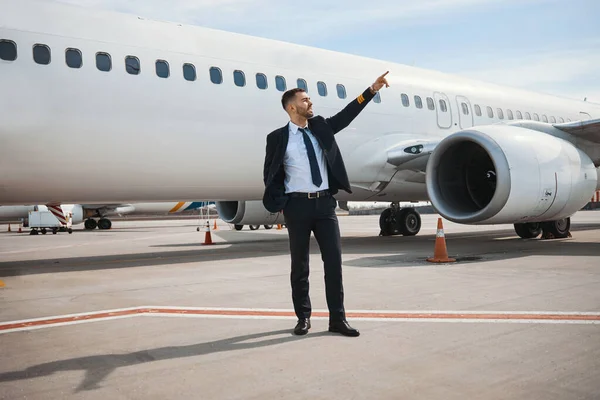 Capitán de avión masculino apuntando con el dedo hacia el sol —  Fotos de Stock