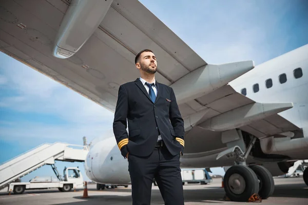 Pewny siebie pilot wpatrujący się w siebie w pobliżu samolotu — Zdjęcie stockowe