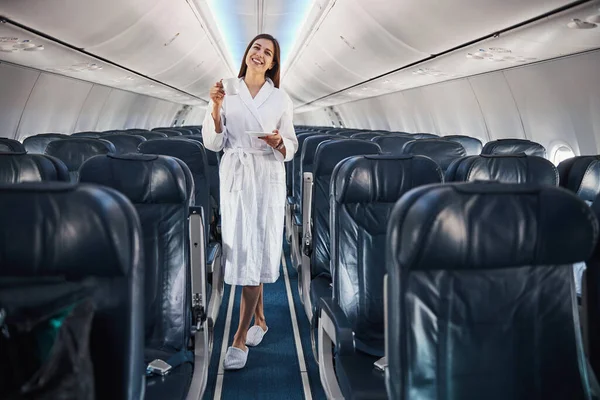 Женщина в домашней одежде поднимает чашку кофе внутри самолета — стоковое фото