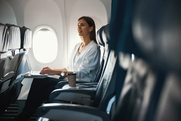 Спокойная женщина, сидящая у иллюминатора самолета одна — стоковое фото