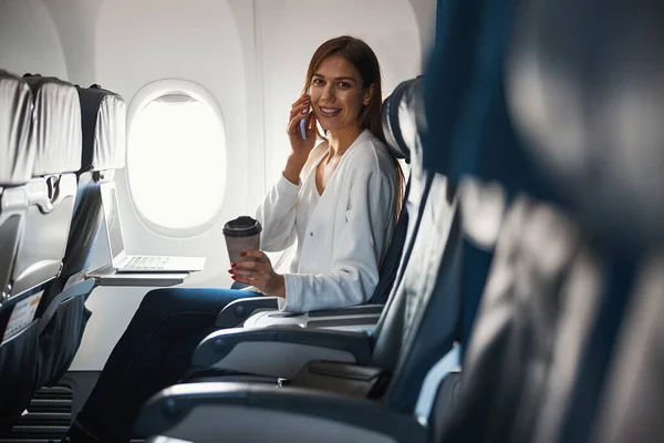 Aantrekkelijke jongedame die telefoneert in het vliegtuig — Stockfoto