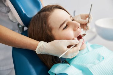 Ağız boşluğunu diş aletleriyle kontrol ettiren genç bir hasta.