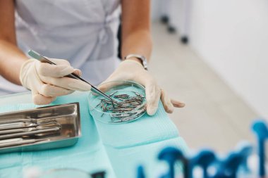 Diş uzmanı cımbızla el aletinin başlığını tutuyor