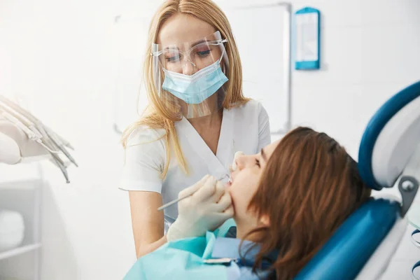 Dişçi kliniği çalışanı küçük hastaların dişlerini inceliyor. — Stok fotoğraf