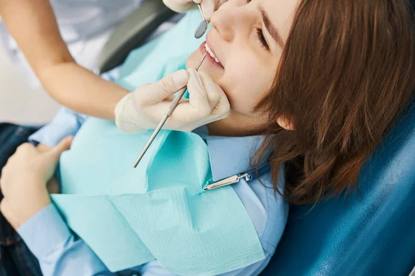 Sonriente niño acostado en silla de dentista durante el examen —  Fotos de Stock