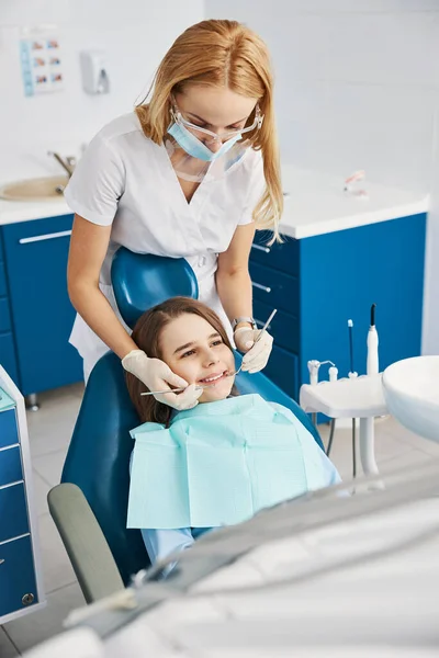 Blondynka dentystyczna pracująca nad zębami dziecka z przyrządami — Zdjęcie stockowe
