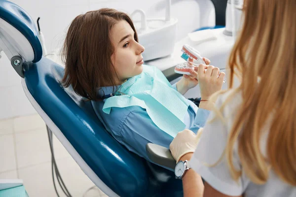 Menino assistindo dentista durante a limpeza dos dentes superiores do modelo dental — Fotografia de Stock