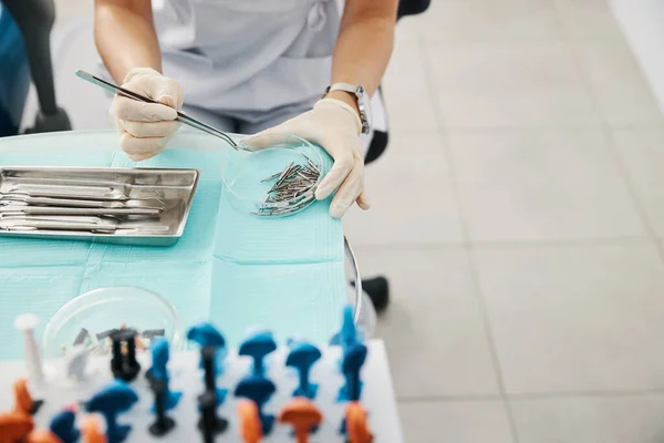 Handen in steriele handschoenen hijsen pincet met gebitsboor — Stockfoto