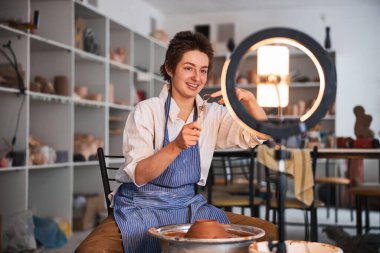 Potter çanak çömlek tekerinin yanındaki cep telefonunda döngü aracını gösteriyor
