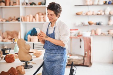 Gururlu çömlek ustası çalışmalarının sonucunu çekiyor.