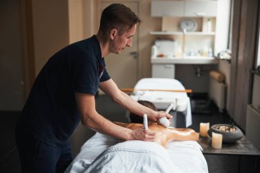 Genç, tanınmamış esmer kadın masaj masasında yatarken sağlık kliniğinde spa ameliyatı oluyor.