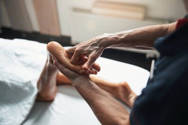 Güzeller güzeli genç bir kadın masaj masasında yatarken masaj terapisi görüyor.