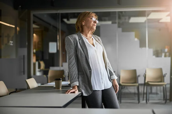 Vrouw leunend op tafel met een hand in het kantoor — Stockfoto