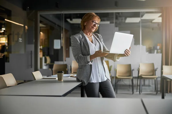 Geschäftsfrau hebt Laptop auf, während sie am Schreibtisch bleibt — Stockfoto