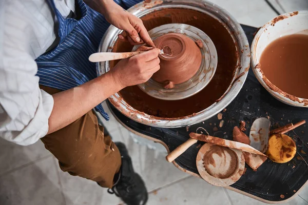 Мастер керамики, формирующий затылок глиняной чаши с помощью инструмента — стоковое фото