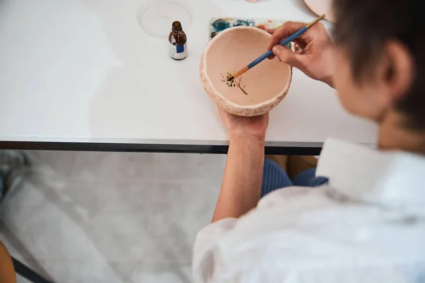 Trabajador en tienda de cerámica pintando hojas de árbol en tazón de barro —  Fotos de Stock