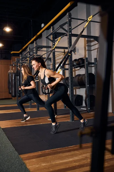 Mujeres atléticas haciendo ejercicio en máquinas de gimnasio de resistencia de tracción — Foto de Stock