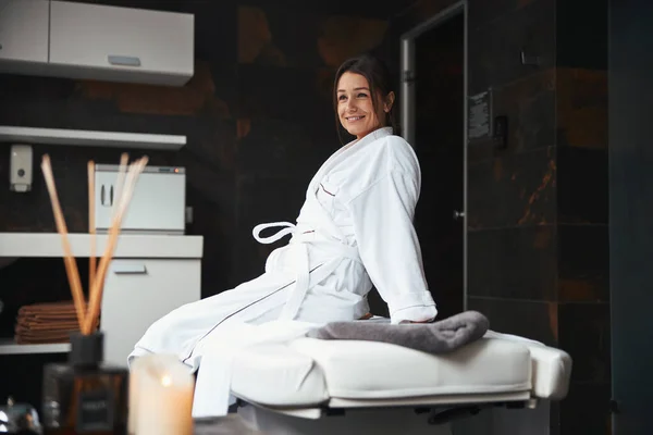 Charmante elegante Geschäftsfrau sitzt auf Massagetisch im Resort-Hotel — Stockfoto