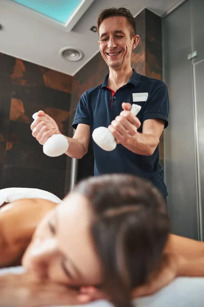 Schöne professionelle Massagetherapeutin, die spezielle Werkzeuge in den Händen hält, während sie nicht traditionelle Massagen durchführt — Stockfoto