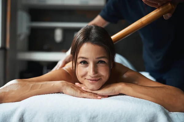 Brunette elegante vrouw ontvangt handmatige massage therapie met houten gereedschap in wellness centrum — Stockfoto