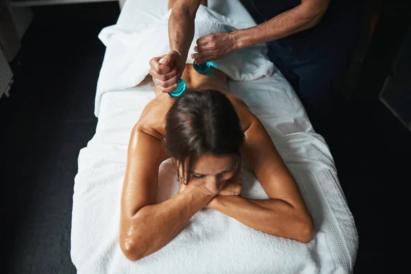 Unerkannte männliche manuelle Therapeutin macht Massage mit kaltem Glas auf dem Rücken des Patienten im Wellness-Center — Stockfoto