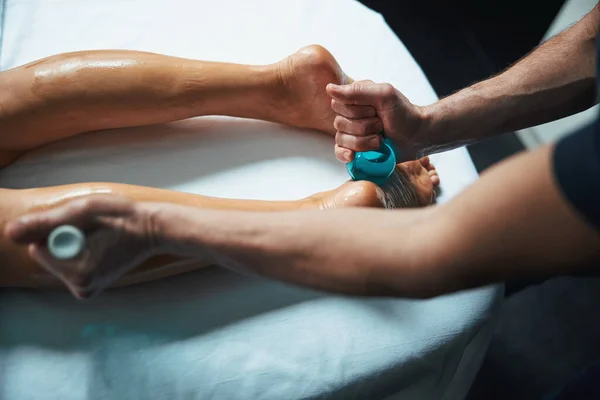 Красивые ноги женщины на белом полотенце во время лечения мужского массажера тела в поликлинике — стоковое фото