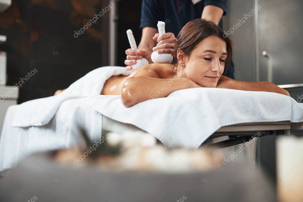 Peaceful happy cheerful woman receiving non traditional massage in spa salon