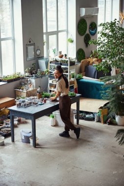 Bir çokyüzlü çiçeğin içini temizleyen neşeli bir çiçek tasarımcısı.