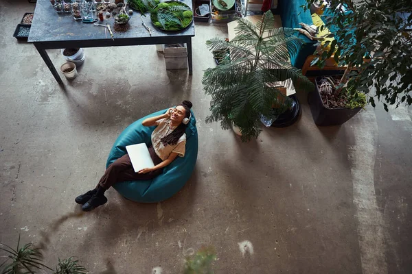 Blomsterhandlare liggande med slutna ögon i en bönpåse stol — Stockfoto