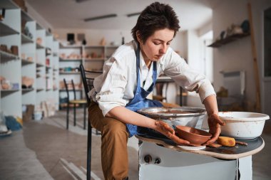 Young attentive master putting bowl on the table