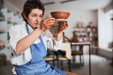 Serious ceramist staring at result of her pottery