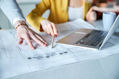 Young designer pointing on sketch during meeting