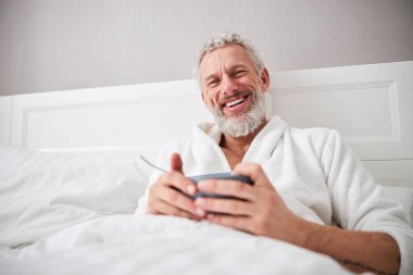 Adult bearded laughing male resting in the morning in home apartment