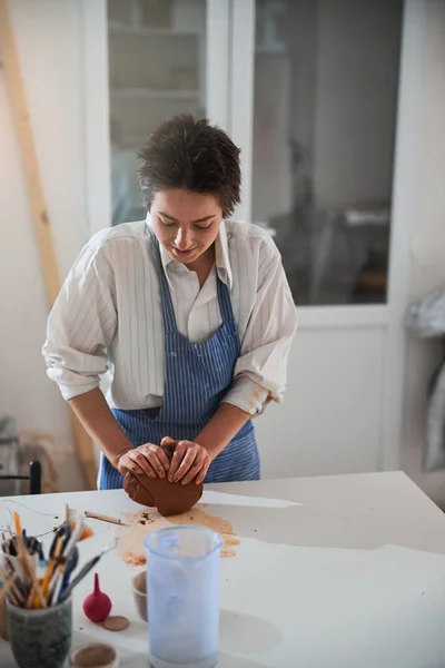 Mulher morena agradável trabalhando com um pedaço de fireclay — Fotografia de Stock