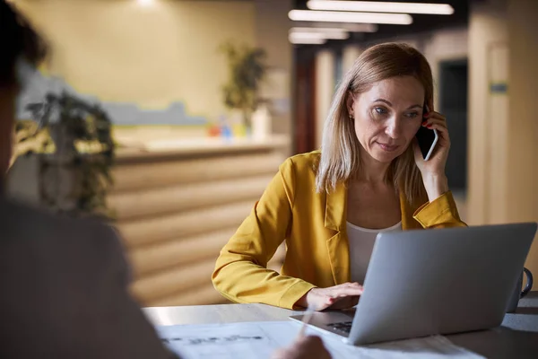 Umtriebige blonde Frau schaut auf den Bildschirm ihres Laptops — Stockfoto