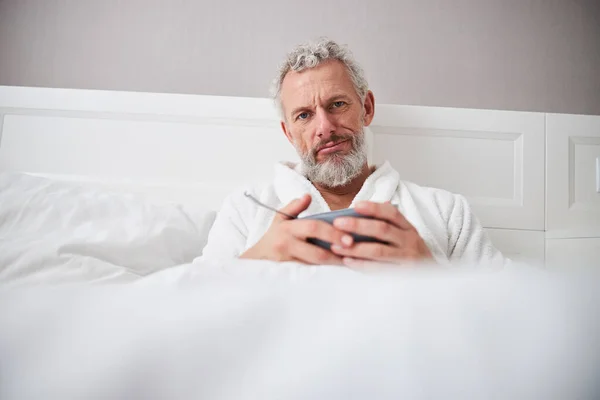 Triste adulto guapo hombre posando y mirando a la cámara de fotos en el dormitorio — Foto de Stock