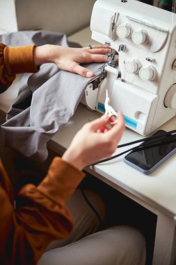 Adult stitching cloth with machine while keeping embroidery scissors