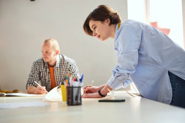 Woman clothes designer checking her sketch with pencil