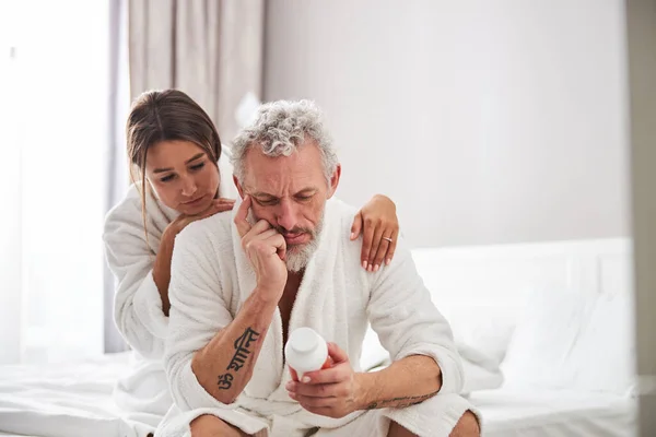 Barbudo caucásico masculino lectura píldoras asignación en moderno apartamento en casa — Foto de Stock