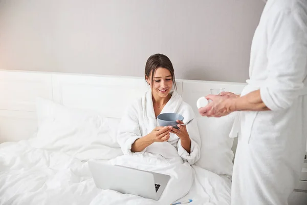 Affascinante donna caucasica elegante trascorrere del tempo al computer portatile mentre si sente male in appartamento a casa — Foto Stock