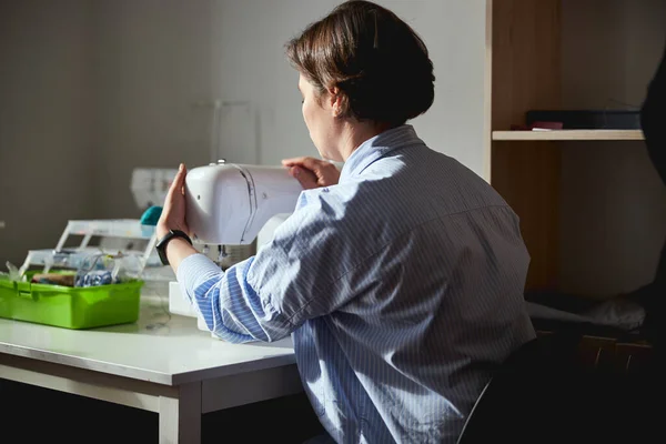 Woman holding a sewing machine on table — ストック写真