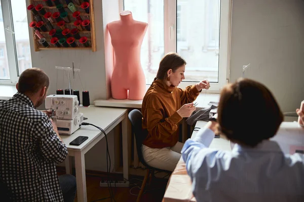 Three people sewing in a bright room — Stock fotografie