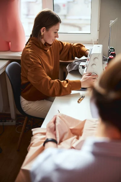 Joven costurera femenina que regula los ajustes de la máquina de coser —  Fotos de Stock