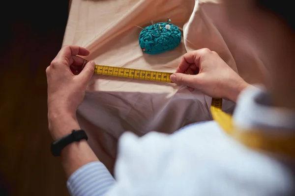 Woman tailor looking at blade of tape measure — ストック写真