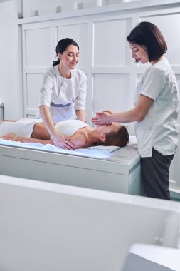 Young redheaded woman lying on massage table in spa salon