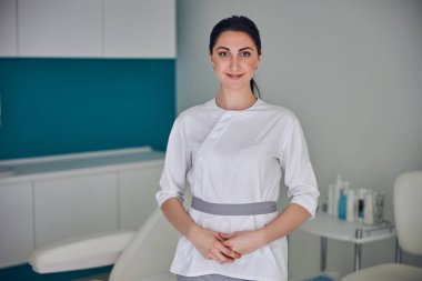 Happy cheerful brunette doctor standing in beauty center