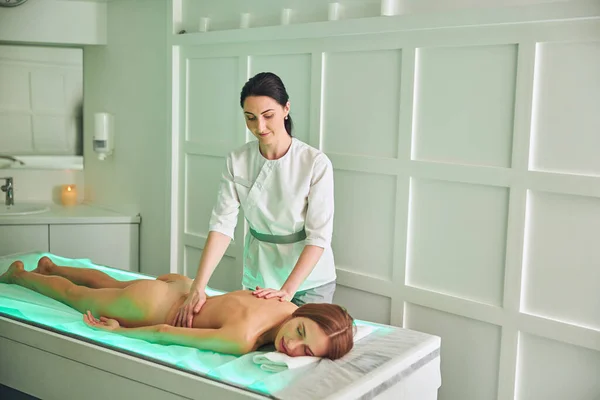 Professionele massage therapeut masseren rug van vrouwelijke cliënt in de kamer binnen — Stockfoto